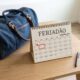 Calendário destacando o dia 7 de setembro de 2026, que cai em uma segunda-feira, ao lado de uma mala de viagem fechada, representando o planejamento para o feriadão