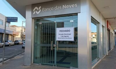Fachada de agência bancária fechada com aviso de feriado municipal em 5 de agosto, dia de Nossa Senhora das Neves, em Ribeirão das Neves