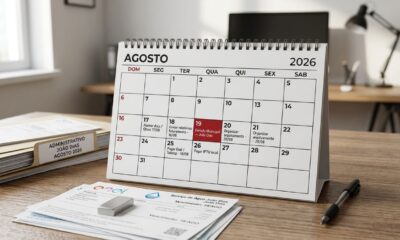 Calendário de agosto de 2026 com o dia 19 destacado como feriado municipal em João Dias, ao lado de boletos e documentos organizados.