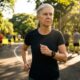 Pessoa acima dos 40 anos caminhando rapidamente em um parque ensolarado e conferindo a frequência cardíaca em um relógio esportivo