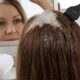 Raiz de cabelo com fios brancos recebendo coloração cremosa, com parte já coberta de forma uniforme e brilhante