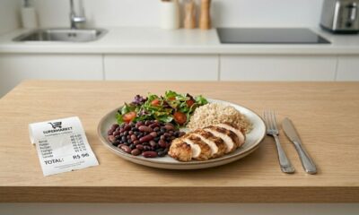 Prato com arroz, feijão, frango grelhado e legumes ao lado de recibo de supermercado de R$ 96
