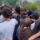 Aglomerado de jovens em confronto físico com um homem mais velho, ao ar livre