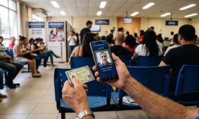 Pessoa usa celular com reconhecimento facial Gov.br e segura documento de identidade em sala de espera