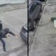 Homem armado saindo de veículo preto e mulher caída no chão após assalto