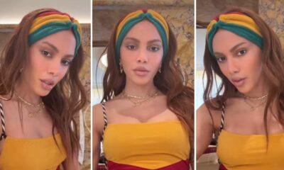Mulher de cabelos castanhos longos, headband colorido, top amarelo e colares dourados