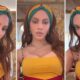 Mulher de cabelos castanhos longos, headband colorido, top amarelo e colares dourados