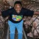 Pelé sorrindo entre fileiras de porcos em baias de metal vestindo camiseta Brasil