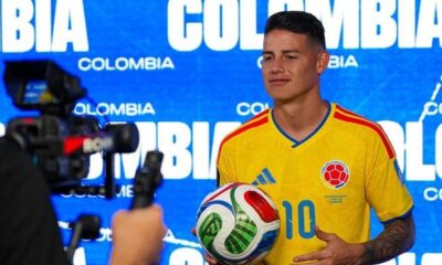 James Rodríguez em camisa amarela da Colômbia número 10, segurando bola de futebol Adidas Brazuca