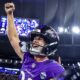 Jogador do Baltimore Ravens em uniforme roxo comemorando, capacete com 'RAVENS', patch 'RIO', em estádio