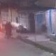 Câmera de segurança noturna mostra rua, moto vermelha, carro e duas figuras escuras