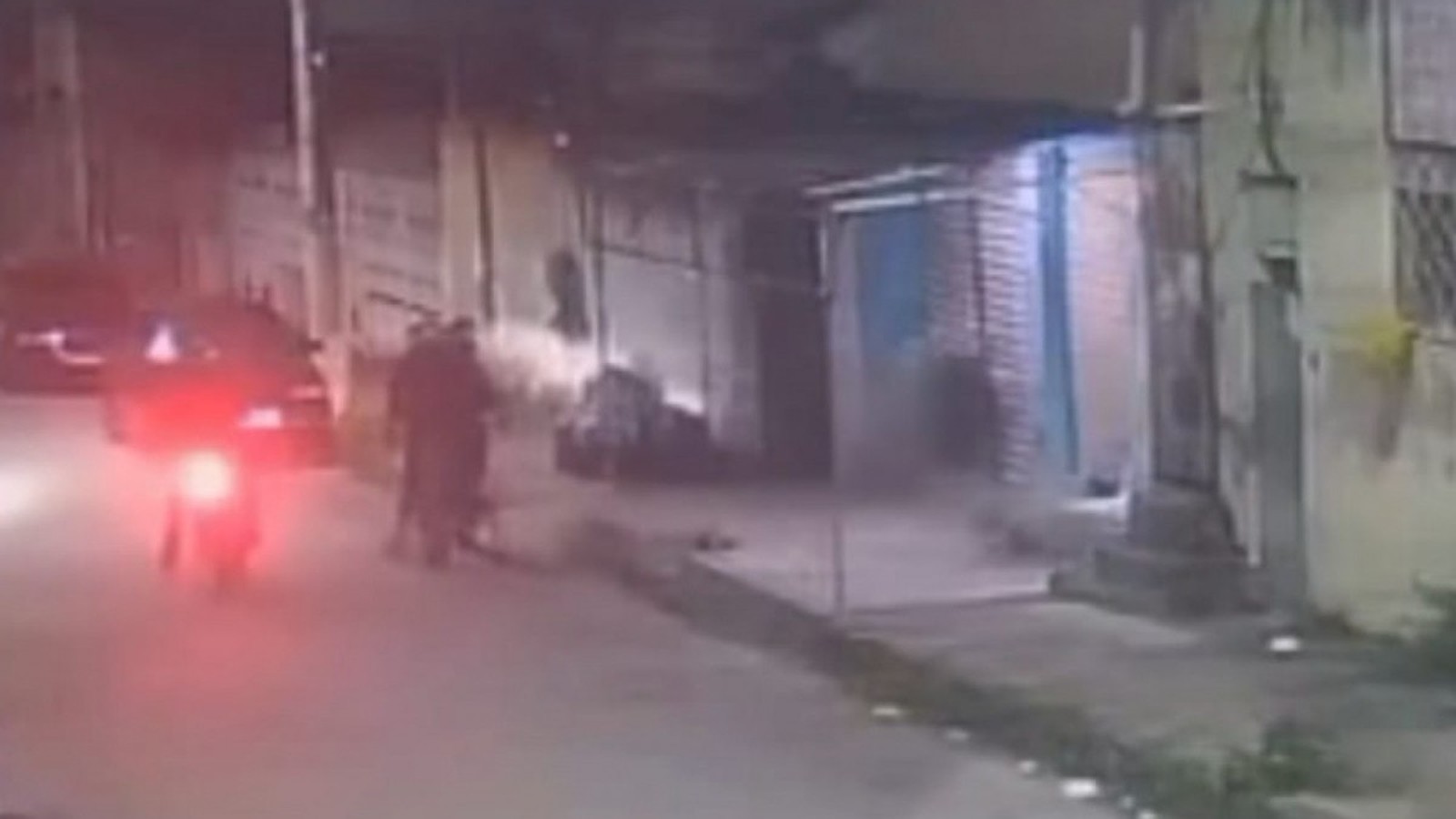 Câmera de segurança noturna mostra rua, moto vermelha, carro e duas figuras escuras