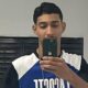 Jovem masculino tira selfie no espelho, segurando smartphone, usa corrente dourada