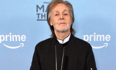 Paul McCartney de jaqueta preta, fundo azul com logotipos Prime Video e PAUL M TH