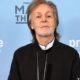 Paul McCartney de jaqueta preta, fundo azul com logotipos Prime Video e PAUL M TH