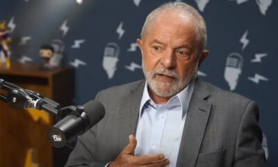 Lula de terno cinza e camisa clara, com barba, fala ao microfone do Flow Podcast