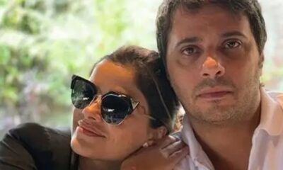Vanessa Giácomo de óculos escuros apoiada em Giuseppe Dioguardi olhando a câmera