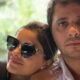 Vanessa Giácomo de óculos escuros apoiada em Giuseppe Dioguardi olhando a câmera