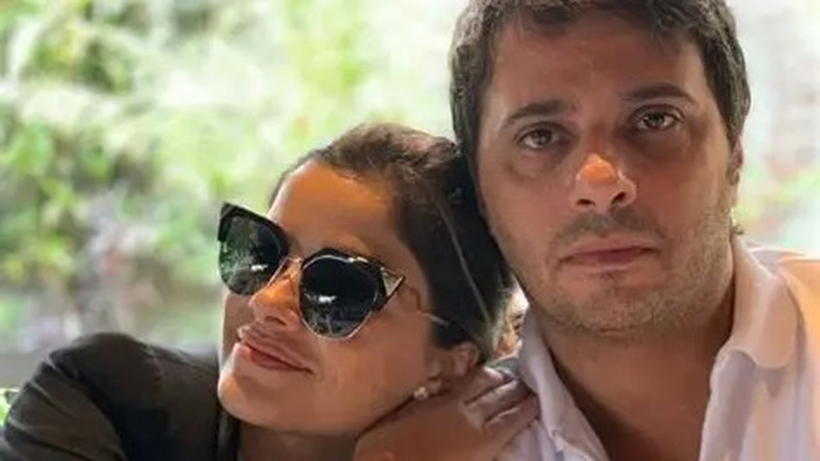 Vanessa Giácomo de óculos escuros apoiada em Giuseppe Dioguardi olhando a câmera