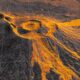 Vista de radar de um vulcão com fluxos de lava laranja brilhante se espalhando sobre um terreno escuro com linhas de grade