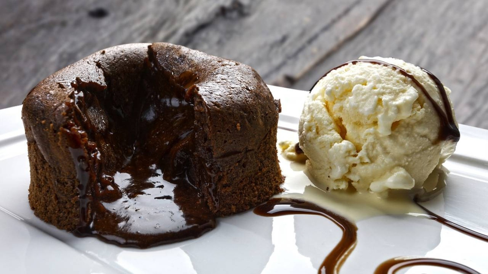 Petit gâteau de chocolate com recheio derretido e sorvete de creme em prato branco