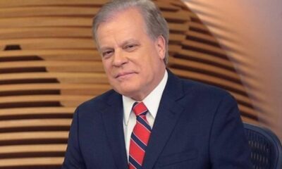 Jornalista Chico Pinheiro, cabelos grisalhos, terno azul escuro e gravata listrada, em estúdio