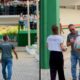 Motorista sorri emocionado recebendo presentes de alunas enquanto estudantes aplaudem em escola