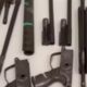Componentes de armas de fogo de alto calibre, como fuzis, dispostas sobre uma superfície branca