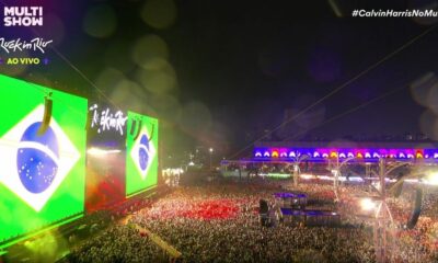 Vista aérea noturna do palco principal do Rock in Rio com telões exibindo a bandeira do Brasil e texto