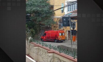 Ambulância vermelha dos Bombeiros com inscrição "AMBULÂNCIA" estacionada em rua de paralelepípedos