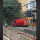 Ambulância vermelha dos Bombeiros com inscrição "AMBULÂNCIA" estacionada em rua de paralelepípedos