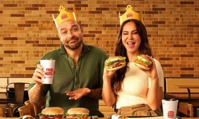 Homem e mulher com coroas Burger King seguram hambúrgueres e copo de refrigerante "FREE REFILL"