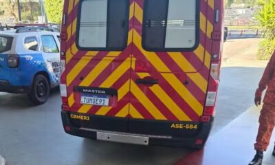 Traseira de van vermelha e amarela listrada ao lado de carro da Polícia Militar azul e branco