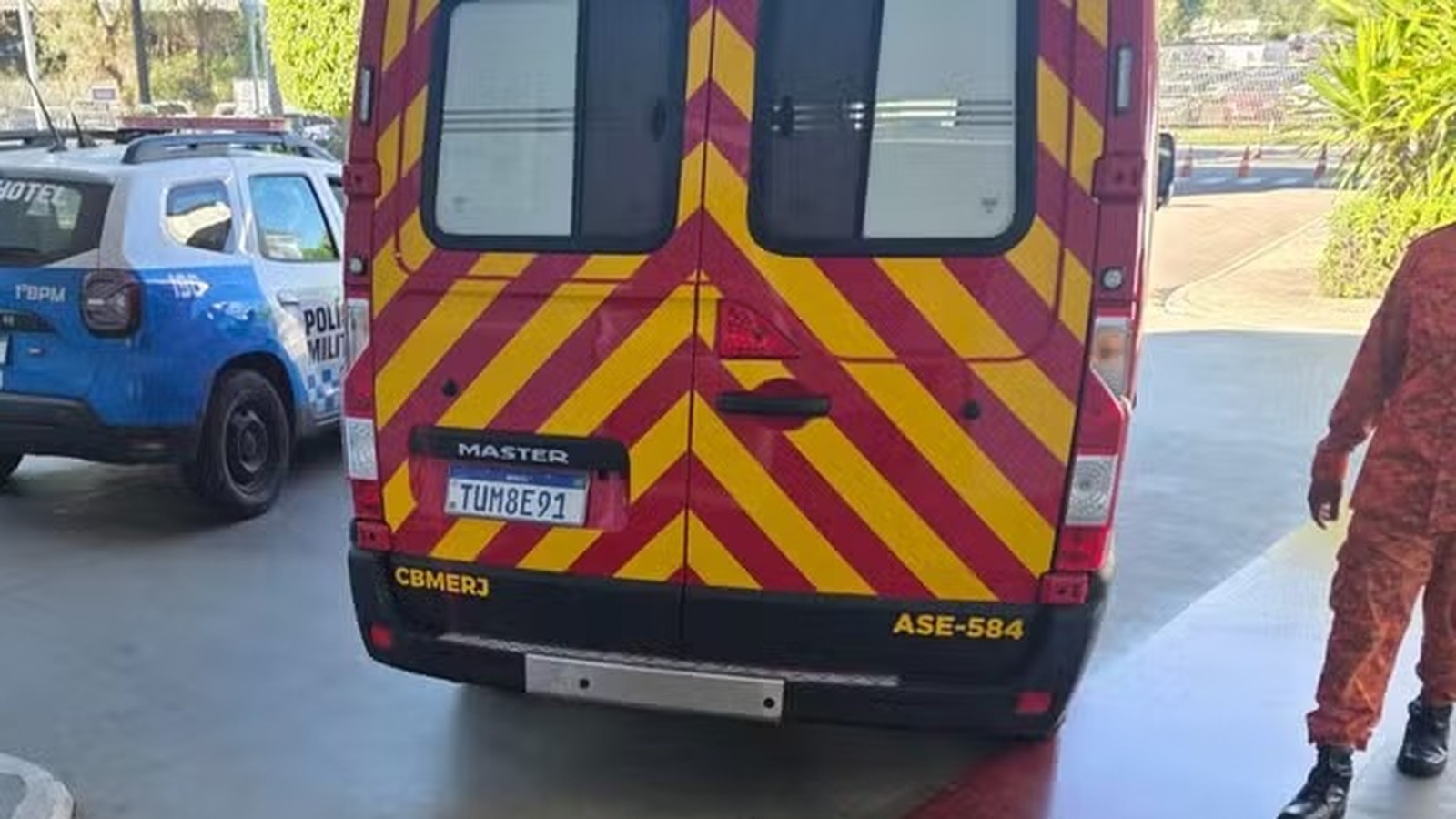 Traseira de van vermelha e amarela listrada ao lado de carro da Polícia Militar azul e branco