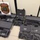 Várias armas de fogo, incluindo fuzis e pistolas, em estojos abertos e escudo da Polícia Federal