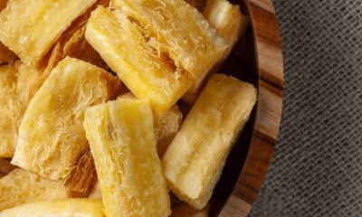 Aipim frito dourado e crocante em tigela de madeira sobre um tecido rústico