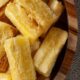 Aipim frito dourado e crocante em tigela de madeira sobre um tecido rústico