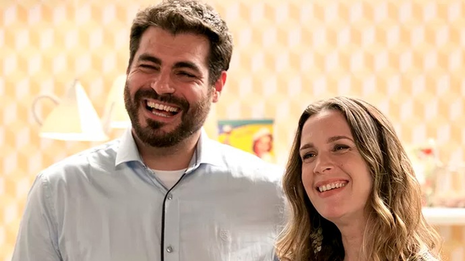 Thiago Lacerda e Vanessa Lóes sorrindo lado a lado, em close-up, com fundo claro