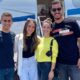 Quatro jovens sorrindo em frente a um jato particular branco e azul