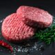 Duas hambúrgueres de carne crua com sal, pimenta preta, alecrim, tomilho e pimenta vermelha