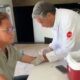Leonardo, de óculos, tem sangue coletado do braço por profissional de jaleco branco