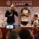 Diretor e dois jovens jogadores em coletiva de imprensa com fundo de patrocinadores e pessoas filmando com celulares