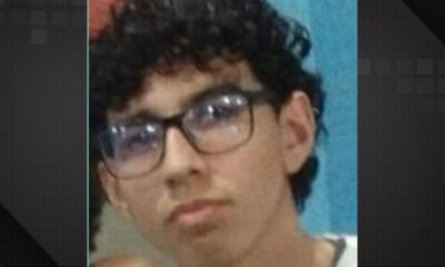 Close-up de jovem com cabelo escuro encaracolado e óculos, olhando para o lado