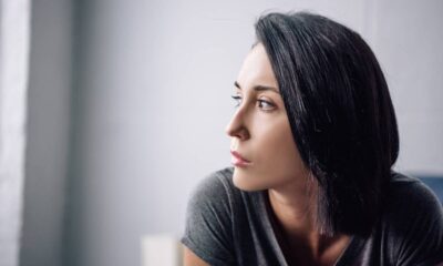 Close-up de perfil de mulher com cabelo escuro e expressão pensativa, olhando para o lado