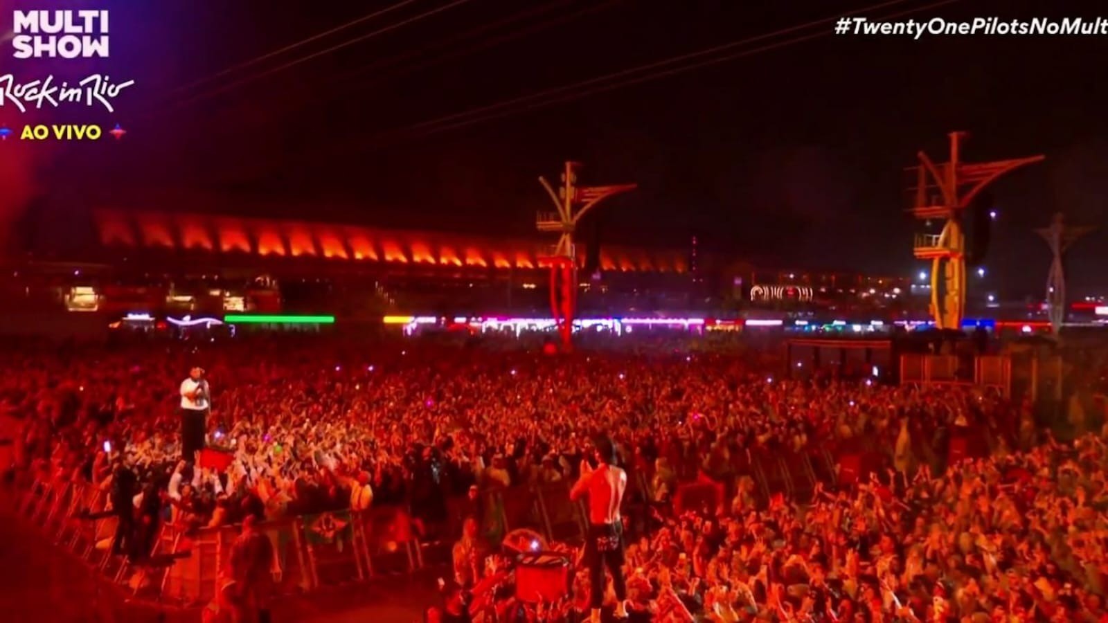 Concert noturno, palco iluminado, multidão Rock in Rio, logotipo Multi Show e hashtag Twenty One Pilots