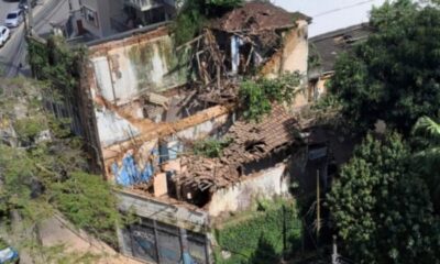 Vista aérea de prédio antigo e parcialmente desabado, com telhado e paredes destruídas e vegetação