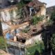 Vista aérea de prédio antigo e parcialmente desabado, com telhado e paredes destruídas e vegetação