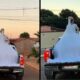 Noiva de vestido branco volumoso na caçamba de caminhonete em rua ao pôr do sol