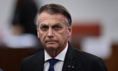 Jair Bolsonaro com semblante sério, usando terno escuro, camisa branca e gravata azul