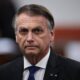 Jair Bolsonaro com semblante sério, usando terno escuro, camisa branca e gravata azul